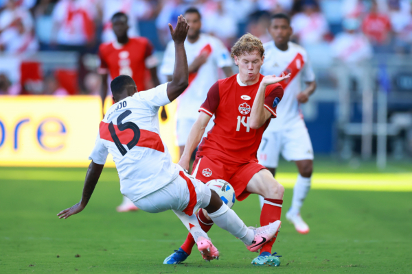 KANSAS CITY, KANSAS - JUNE 25: Miguel Araujo of Peru challenges for the ball with Jacob Shaffelburg of Canada during the CONMEBOL Copa America 2024 between Peru and Canada at Children's Mercy Park on June 25, 2024 in Kansas City, Kansas. 